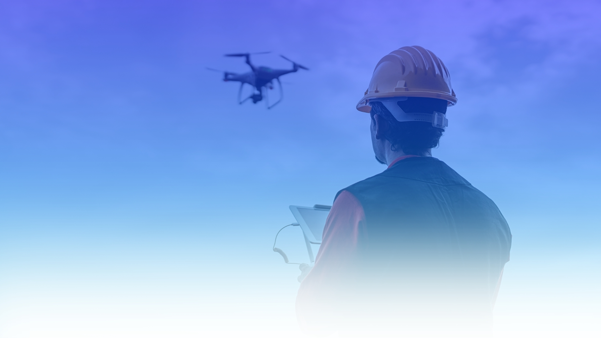 Operario con casco observando un dron en vuelo en un entorno de trabajo